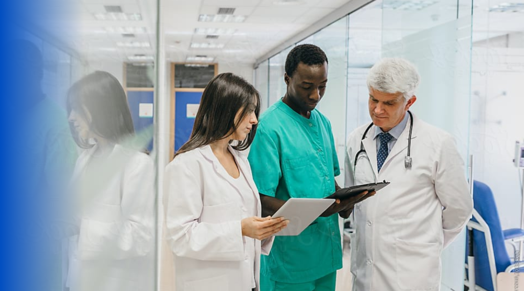 Doctors stand together in a hallway looking at a chart